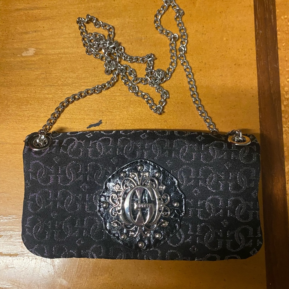 Guess black monogram shoulder bag with a silver emblem and chain strap.